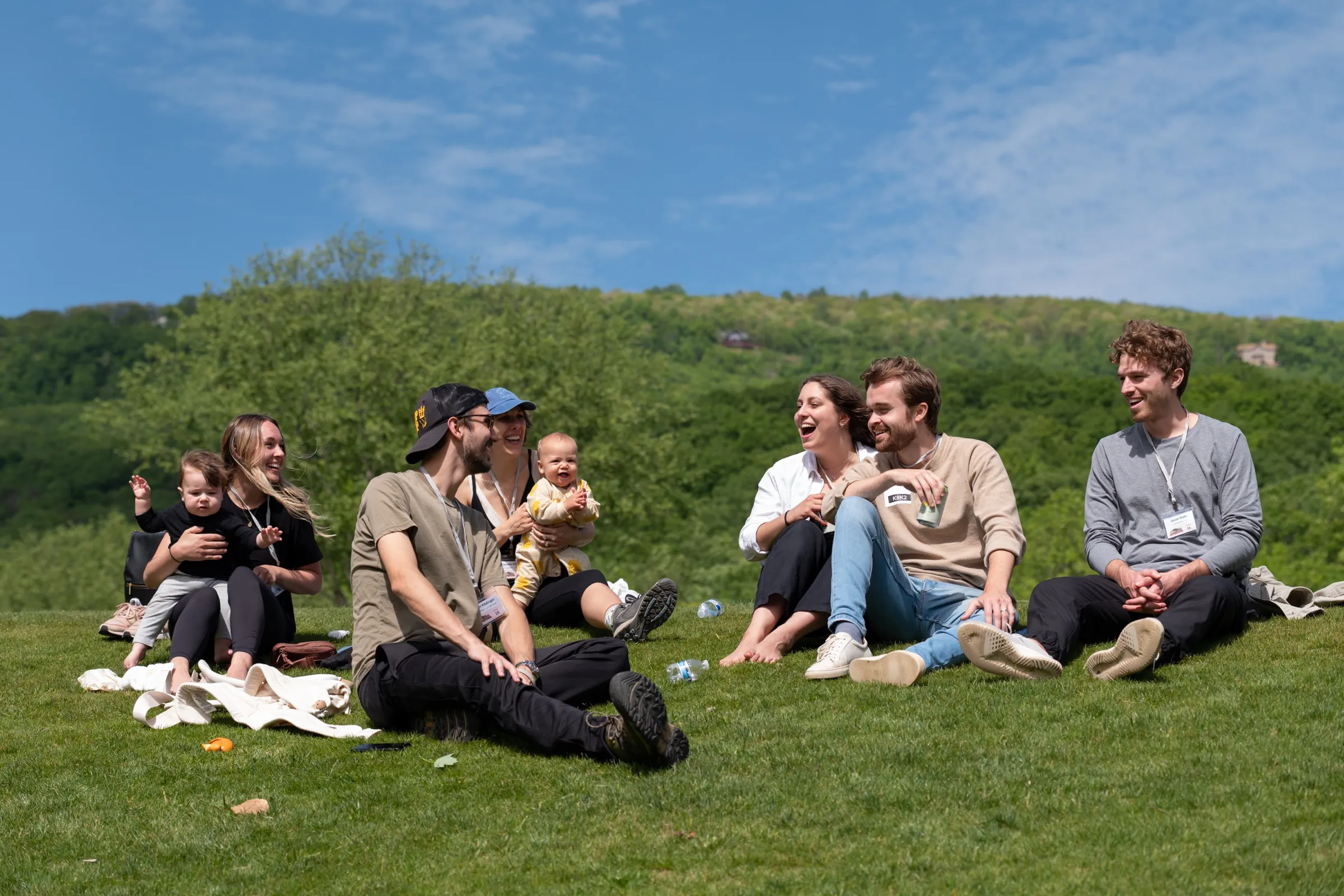 Group sitting on a grassy hillside, laughing together