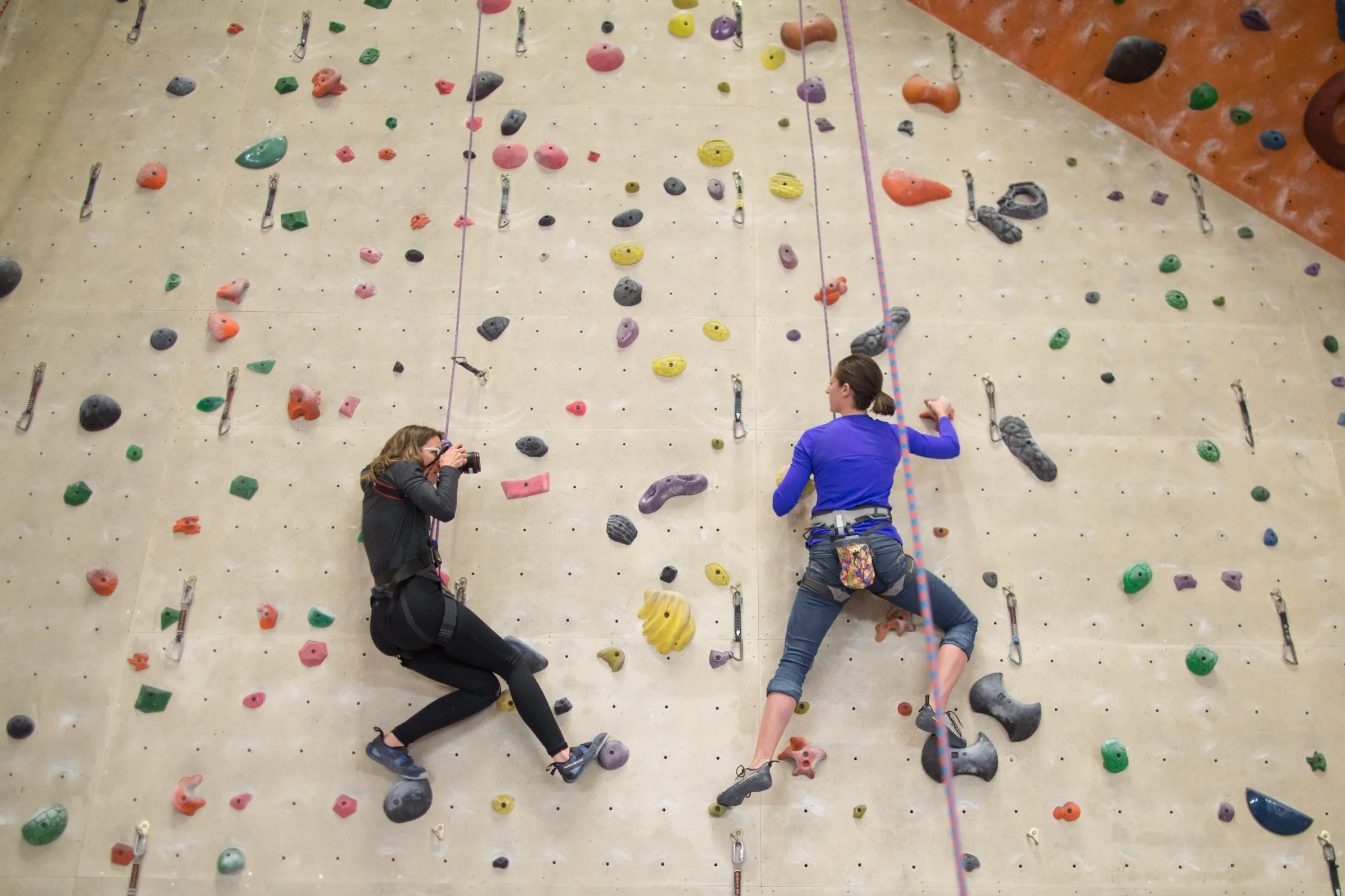 Annie Smith photographing a climber on an indoor climbing wall