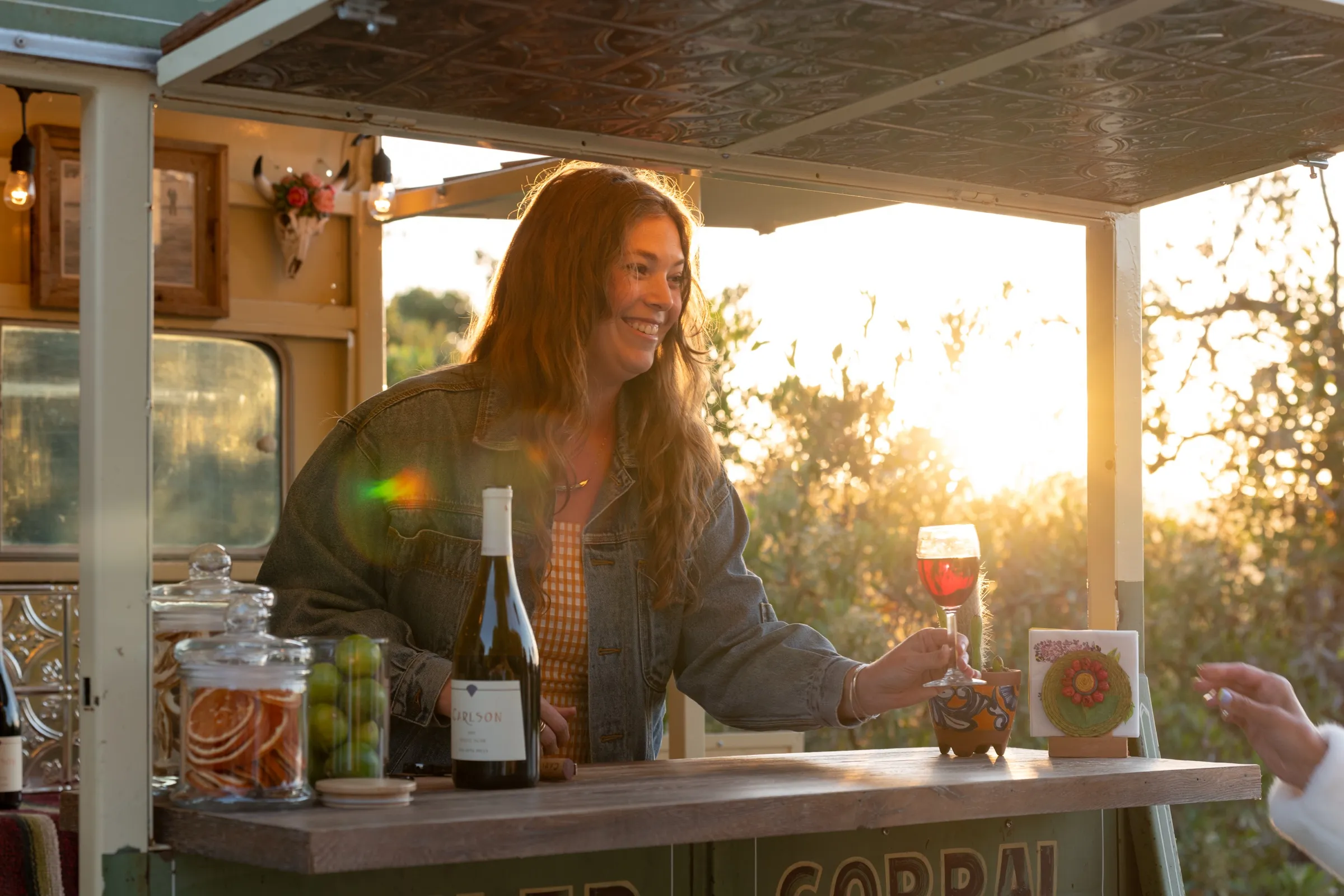 Bride and groom toasting with wine in front of a vintage bar trailer