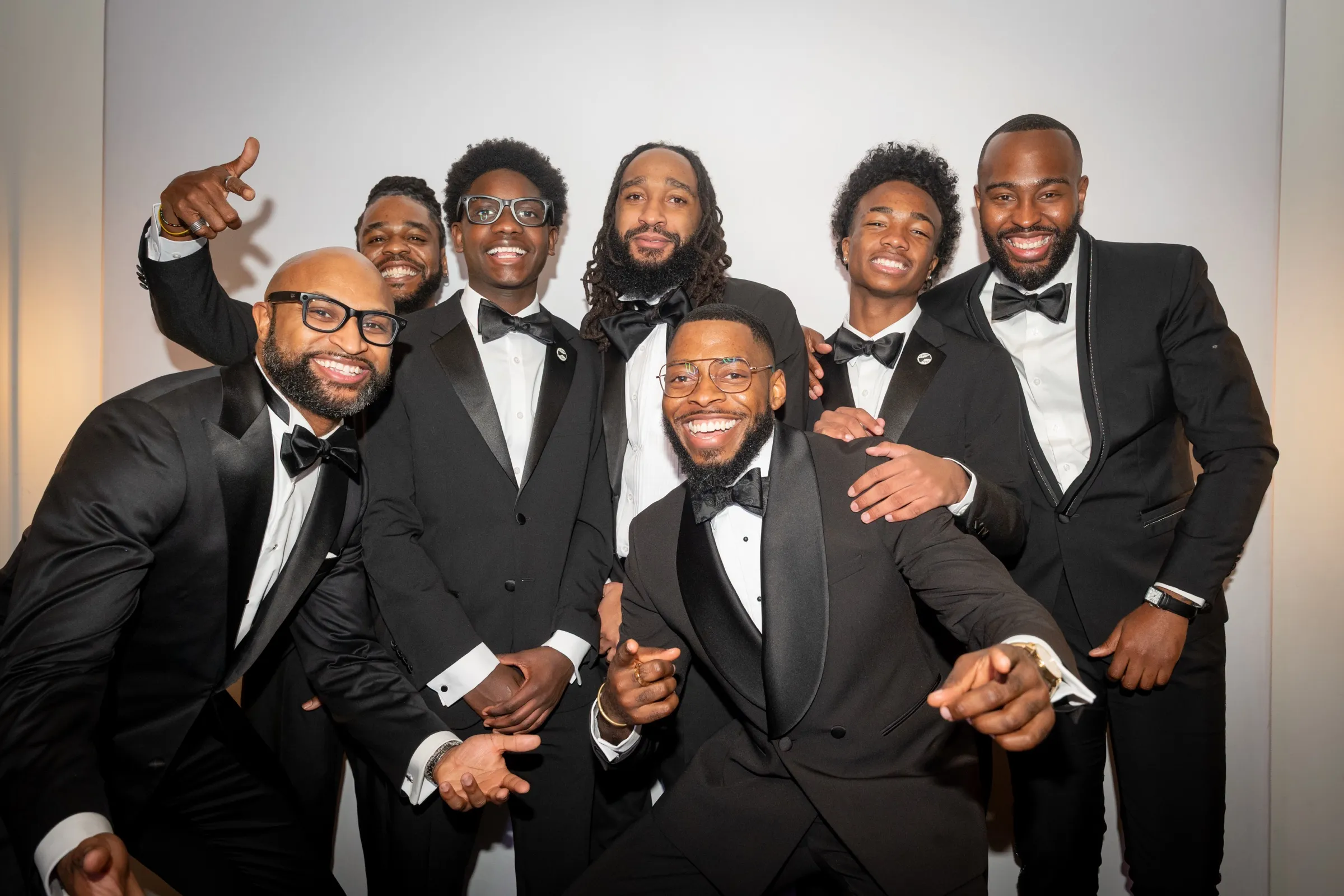 Group of men in tuxedos laughing together at a gala