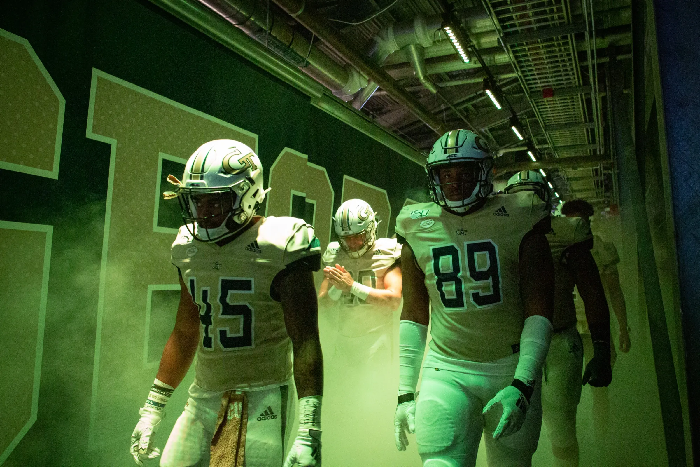 Football players walking through a dramatically lit stadium tunnel