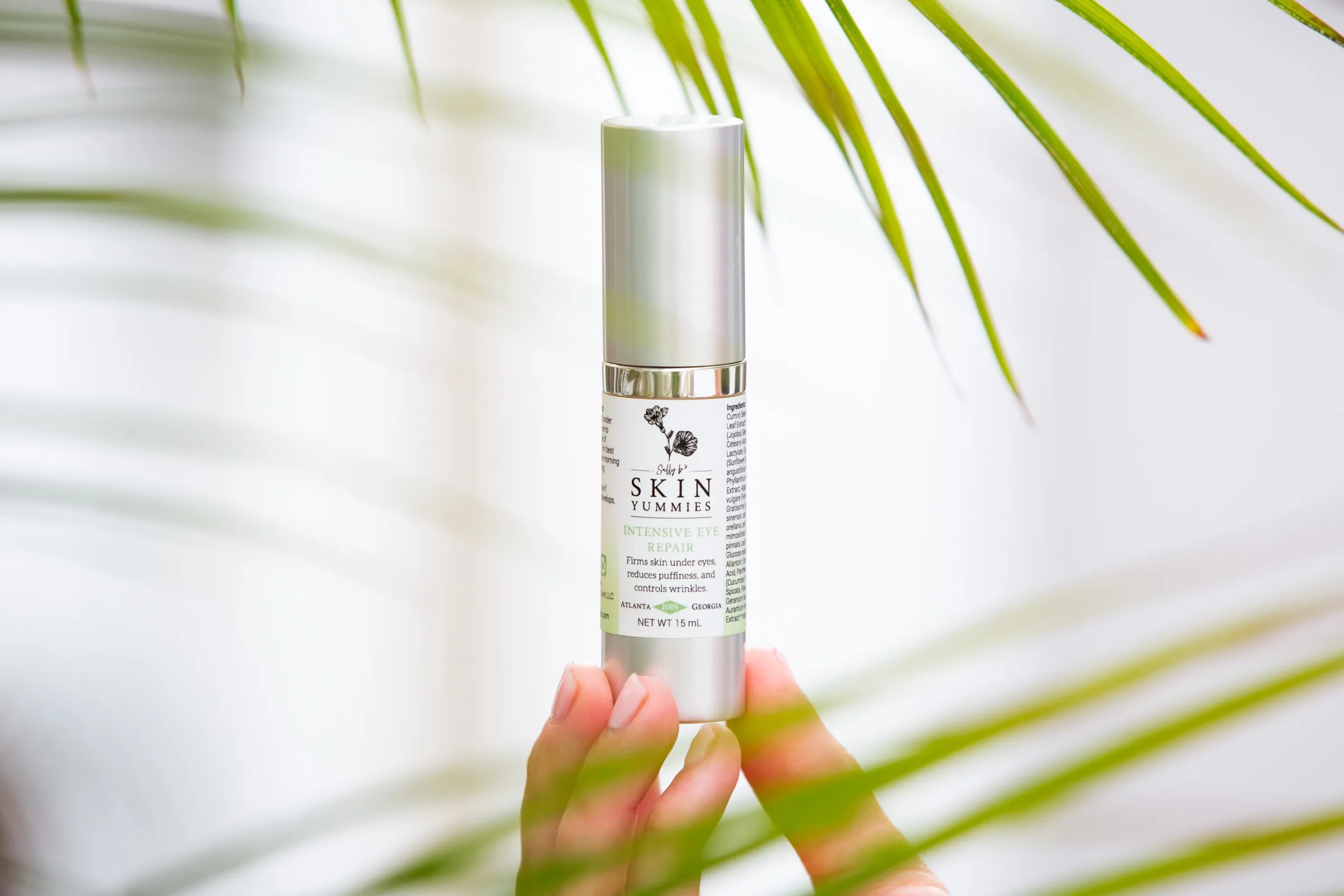 Skincare product held up against green palm fronds